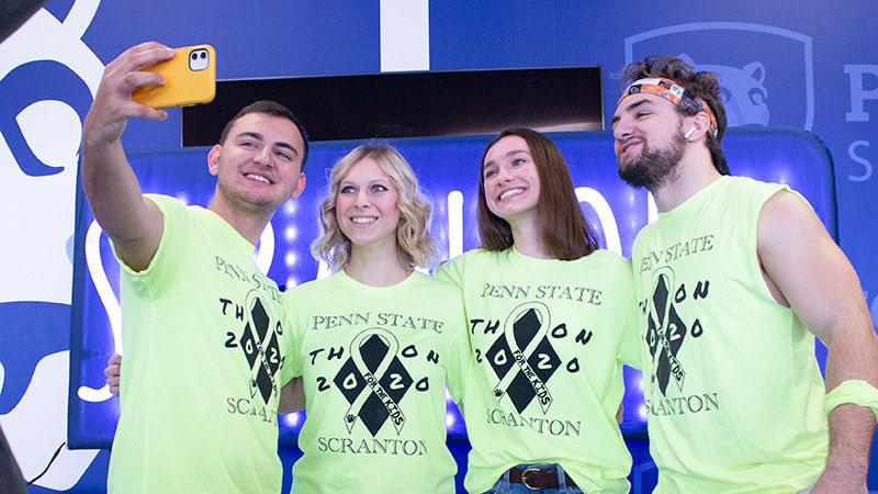 four students in bright yellow Scranton THON t-shirt pose for selfie