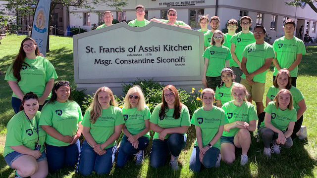 student volunteers at local soup kitchen pose for a photo in front of the facility
