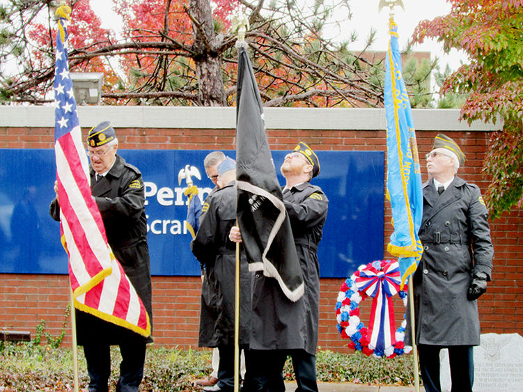 veterans holding US and state flags at veterans day ceremony