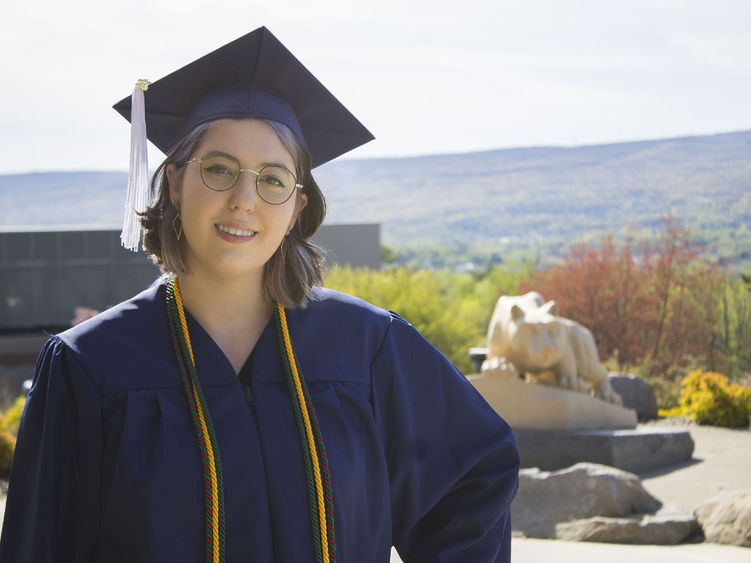 Student wearing commencement regalia and smiling