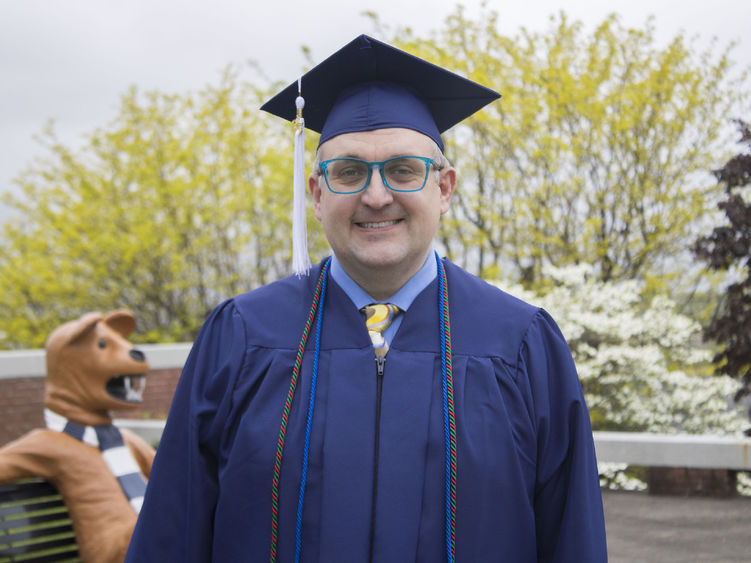 Student wearing commencement regalia and smiling
