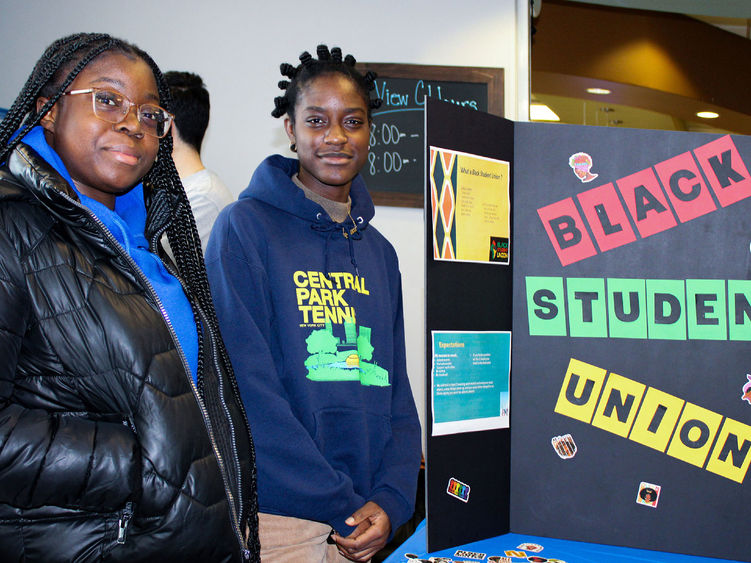 Black student union leaders pose for a photo next to a display promoting their group on campus