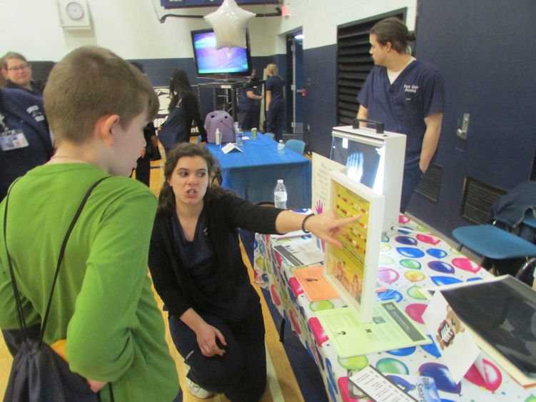 nursing student talking to child at info table