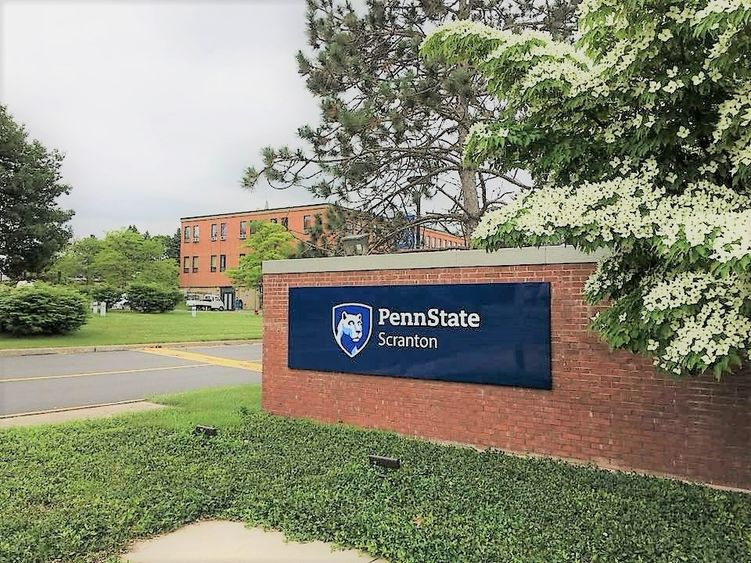 entrance to the campus with the red brick entrance sign reading Penn State Scranton and campus logo