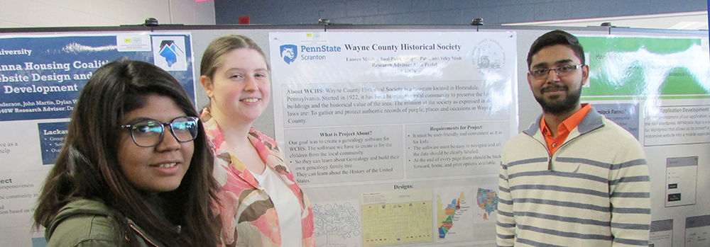 Students at past research fair displaying their research poster