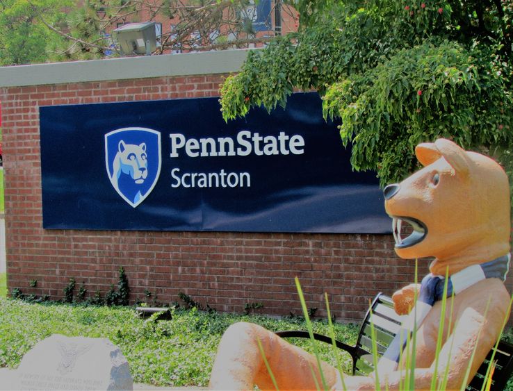 Nittany lion mascot seated on bench at scranton campus entrance