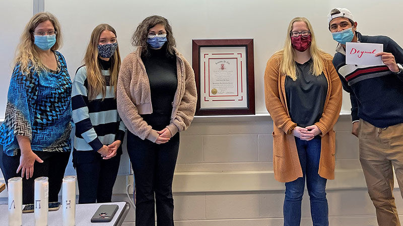 Current and newly inducted members of Lambda Pi Eta pose for a group photo after induction ceremony