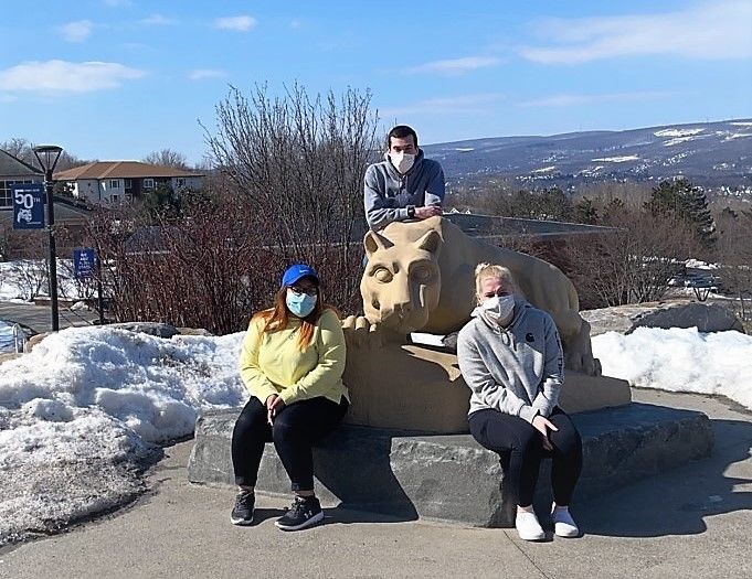 Three campus lion ambassadors pose for a photo at the Nittany Lion Shrine