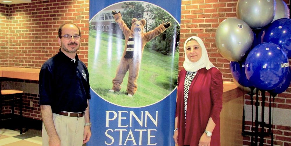 Chancellor Marwan Wafa and his wife Sahar standing in front of Penn State banner