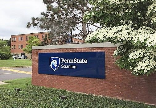 Front entrance to campus with brick wall and sign