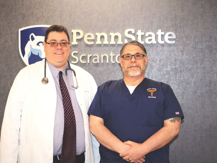 photo of Mike Evans and Frank Turnbaugh standing in front of wall with Penn State Scranton campus logo