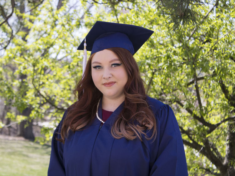 Student wearing commencement regalia and smiling