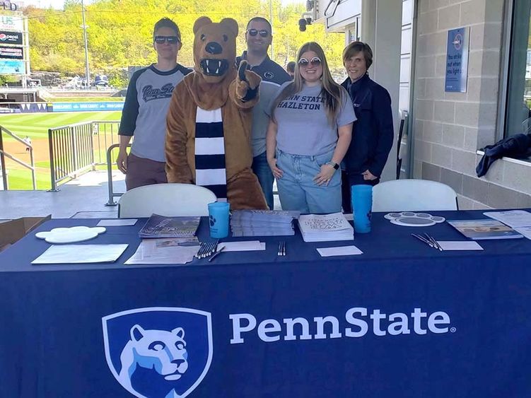 A group of people standing behind a table on a baseball stadium concourse.