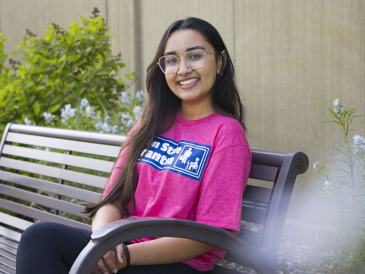 Student sits on bench and smiles