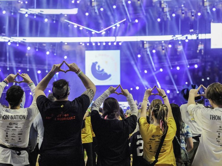 Scranton THON dancers face the stage and make the Four Diamonds symbol with their hands