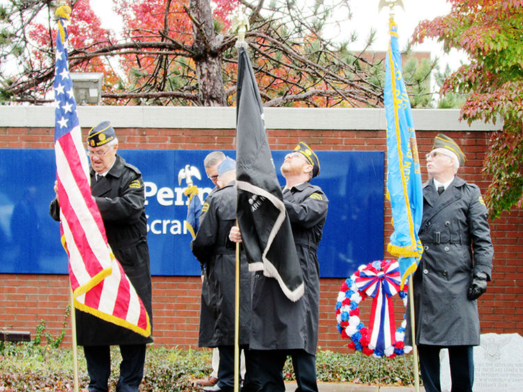 four veterans in uniform raise flags at Penn State Scranton in ceremony