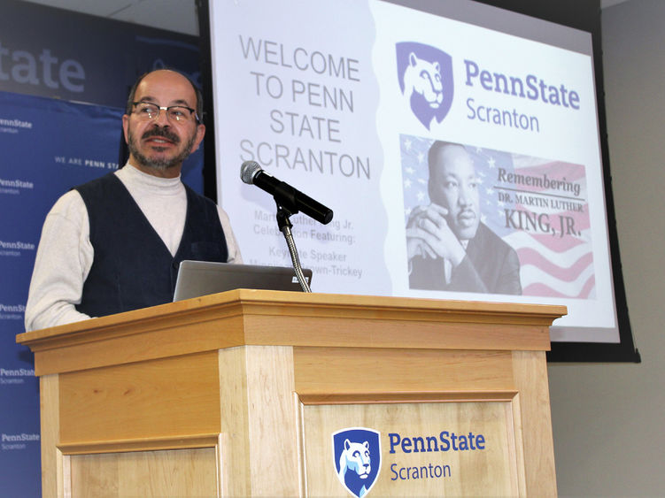 Chancellor Marwan Wafa speaking at podium with MLK Jr image on screen behind him